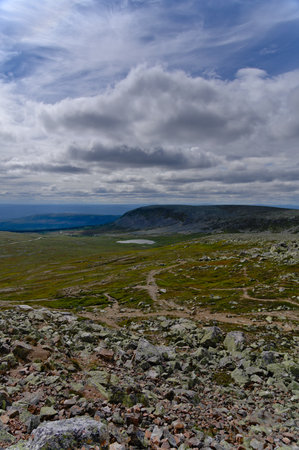 In the middle of Scandinavian nature, elevated view from rocky mountain peak outcrop view of tundra valley landscape and mountain with cloudscape in a remote national park Swedenの写真素材