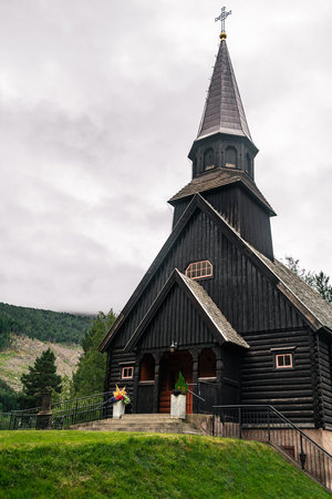 GjÃ¸ra Chapel sits in GjÃ¸ra village, offering a view of its striking wooden historic building against a backdrop of green mountains and overcast skies, MÃ¸re og Romsdal county Norwayの写真素材