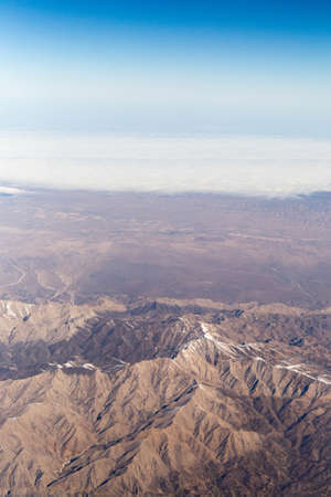 Clouds mountains and sky as seen through window of an aircraft of uzbekistanの写真素材