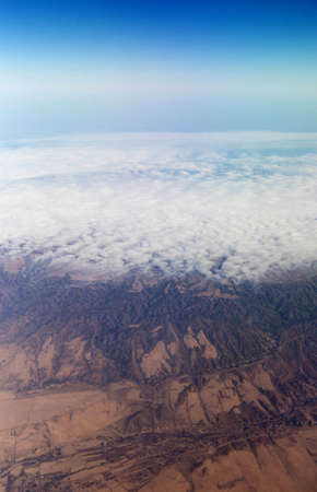 Clouds mountains and sky as seen through window of an aircraft of uzbekistanの写真素材