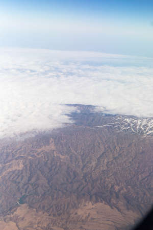 Clouds mountains and sky as seen through window of an aircraft of uzbekistanの写真素材