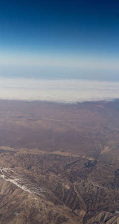 Clouds mountains and sky as seen through window of an aircraft of uzbekistanの写真素材