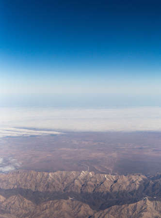 Clouds mountains and sky as seen through window of an aircraft of uzbekistanの写真素材