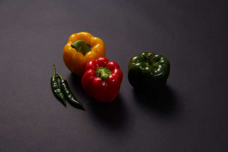 Red green yellow pepper in the kitchen black beautiful backgroundの写真素材