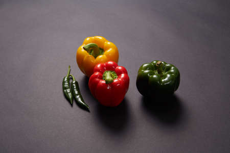 Red green yellow pepper in the kitchen black beautiful backgroundの写真素材