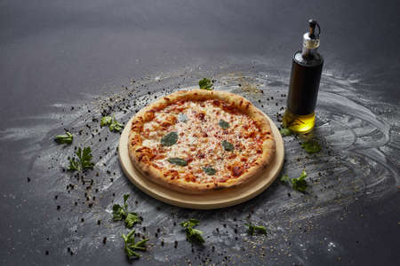 Italian delicious fresh pizza with tomato and pepperoni on a dark background.  Pizza on the black...