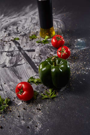 Whole and cutted tomato in ingredients of pizza on italian black paper tableの写真素材