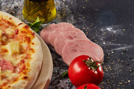 whole italian pizza on wood table with ingredients in black tableの写真素材