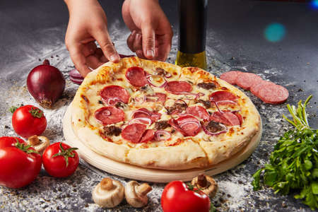 whole italian pizza on wood table with ingredients in black tableの写真素材
