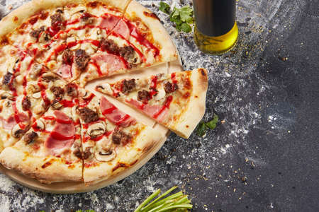 whole italian pizza on wood table with ingredients in black tableの写真素材