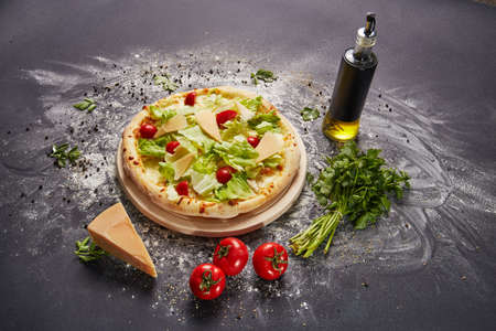 whole italian pizza on wood table with ingredients in black tableの写真素材