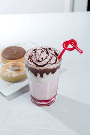 Glass of strawberry milkshake with whipped cocolate cream and fresh strawberries on pinkの写真素材