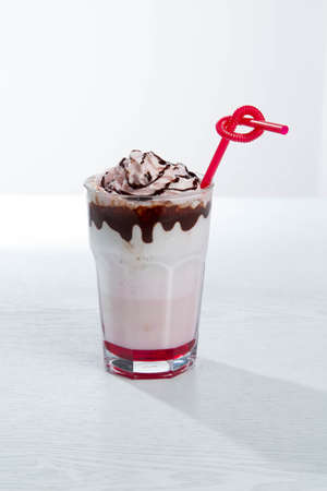 Glass of strawberry milkshake with whipped cocolate cream and fresh strawberries on pinkの写真素材