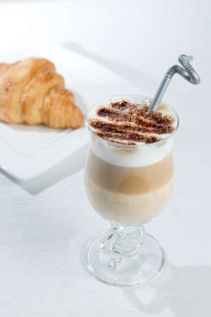 Glass of cold latte coffee topic cocolate cream on isolated white background with dessertsの写真素材