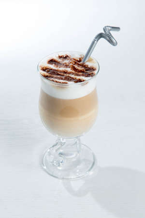Glass of cold latte coffee topic cocolate cream on isolated white background with dessertsの写真素材