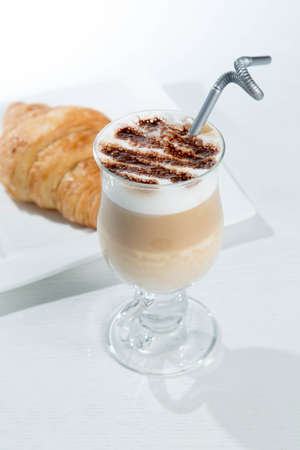 Glass of cold latte coffee topic cocolate cream on isolated white background with dessertsの写真素材