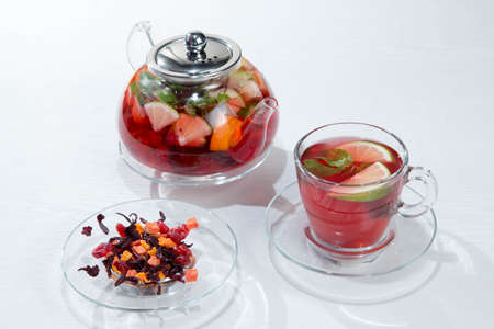 Red fruit and berry tea with raspberries in a glass teapot with mint isolatedの写真素材