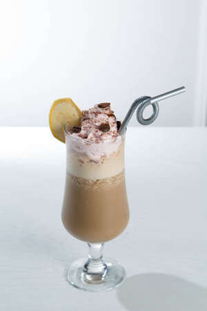 Glass of cold latte coffee topic cocolate cream on isolated white background with bananaの写真素材