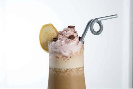 Glass of cold latte coffee topic cocolate cream on isolated white background with bananaの写真素材
