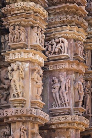 Cultural heritage of India - the sculptures made of sandstone, couple in one of Kamasutra's poses, deities and people on a wall of the temple of Kandariya-Mahadeva, Khajuraho, the Province of Madhya Pradesh.の写真素材