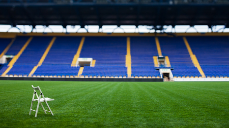 The lonely white chair on the green football field of the stadium, waits for the one who will enjoy full immersion in the forthcoming match.の写真素材