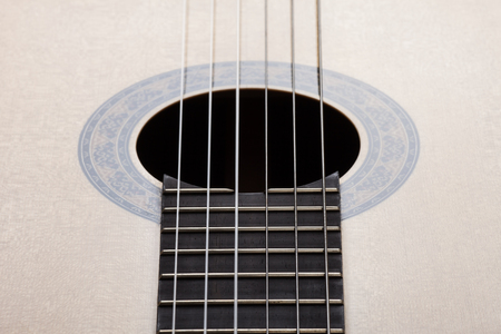Resonator of a sound board of a classical acoustic guitar with the strings passing through it. Close...