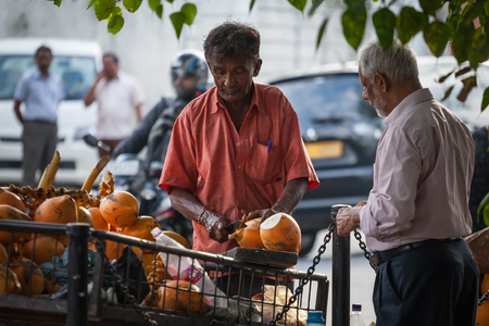 The man sells from the cart orange drinking cocoes on the street of the city. Sri Lanka, Colombo, on January 21, 2017のeditorial素材