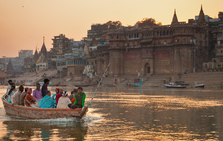 The boat with indian pilgrims floats across Ganges along the embankment of Varanasi at sunset. India, Uttar Pradesh, on February 6, 2014.のeditorial素材