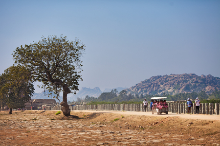 Young schoolgirls in pink dresses, and tourists move in different directions, on the road of the leader to sights of Hampi, India, Karnataka, vicinities of Hampi, on January 10, 2018のeditorial素材