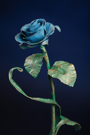 The metal rose with a blue bloom and a green stalk, on blue background.の写真素材