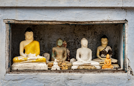Several modern figurines of Buddha of the different size and workmanship, stand in a niche at one of Buddhist temples of Sri Lankaの写真素材