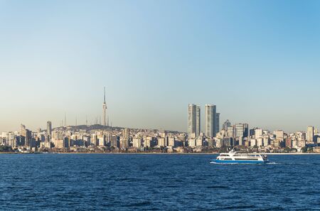 A pleasure ship floats against the backdrop of skyscrapers and residential buildings of the Asian...