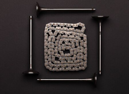 Studio photography - four gas distribution valves lie in a square, surrounding a gas distribution chain, rolled up by a snake, on a flat surface isolated on a black background.の写真素材