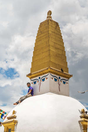 A man sit on a white stupa, with a brush in his teeth, make of a break in time of restoration work on Boudha. June 14, 2020, Kathmandu, Nepal.のeditorial素材