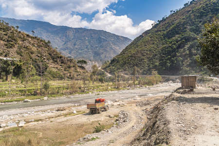 A brightly painted truck stand on a stoned bank of a mountain river in the middle of a valley in the Himalayas, Nepal.のeditorial素材