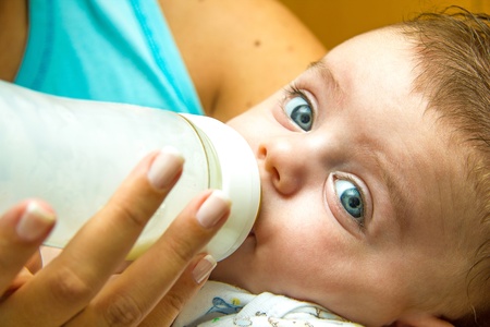 Mother giving milk in a bottle to her babyの写真素材