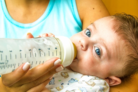 Mother giving milk in a bottle to her babyの写真素材