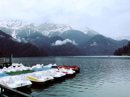 Blue lake, boats, mountains, snowy peaks, fogの写真素材