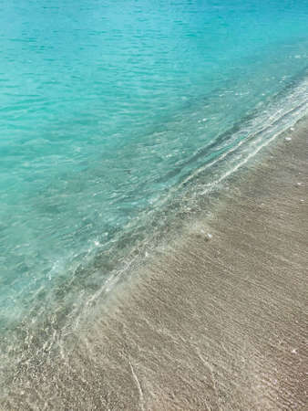 The waves of the ocean roll onto the sandy shoreの写真素材