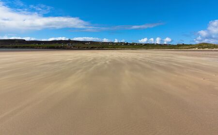 Dunnet Bay is a sand and shingle rural beach backed by some grass covered dunes.This photo shows the beach, where sand is flowing over the beach on a windy day.の写真素材