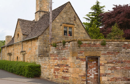 an old cottage with a bricked-up entrance in the wall adorns a street in Broadway in the English Cotswoldsの写真素材