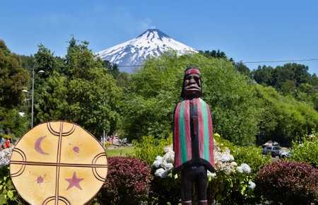 Beautifully painted Mapuche art objects with the active Villarica volcano in the background - seen in Pucon, Chileの写真素材