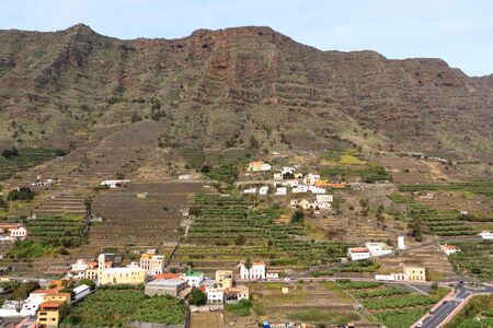 view to the village Hermigua on Canary island La Gomera with multi colored houses and palm treesの写真素材