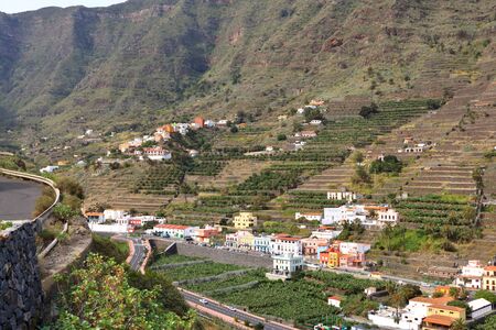 view to the village Hermigua on Canary island La Gomera with multi colored houses and palm treesの写真素材
