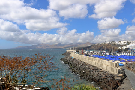 March 08 2018 - Puerto del Carmen, Lanzarote, Canary Islands in Spain: day view of boardwalk with palms and beach in Puerto del Carmenのeditorial素材