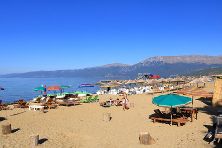 September 11 2023 - Pogradec in Albania: Ohrid Lake shore with some people and boats in the late summerのeditorial素材