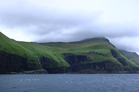 a view to Mykines Island showcasing towering cliffs surrounded by the expansive North Atlantic Ocean, Faroe Islands, Denmarkの写真素材