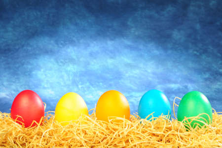 five painted eggs on a straw on a blue backgroundの写真素材