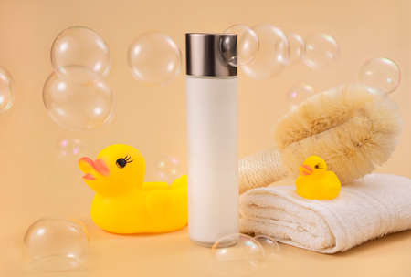 bottles with cosmetic foam or gel, bathroom accessories, soap bubbles and rubber ducks on beige...