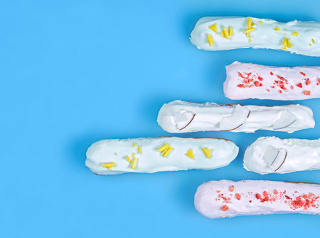 Delicate custard cakes eclairs on a blue background